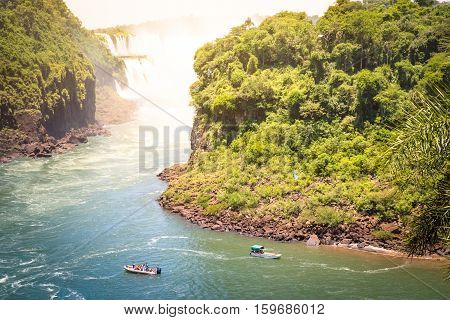 Detail of Iguazu Fall from mirador of Isla San Martin between argentinian and brazilian river side with motorboat dinghy - Waterfalls nature wonder of South America continent - Vivid saturated filter