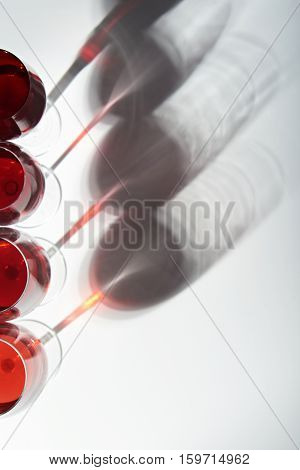 Shadows from red wine glasses on white background view from top
