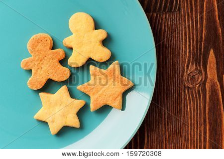 Gingerbread cookies man and star shape in turquoise plate on wooden table with copyspace
