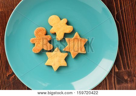 Gingerbread cookies man and star shape in turquoise plate on wooden table overhead view