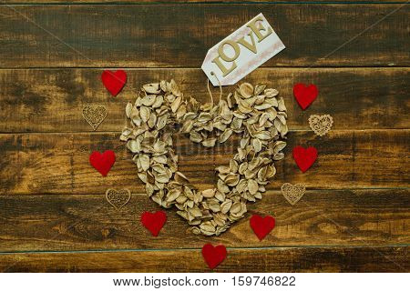 Heart maked with dry petals on a wooden background