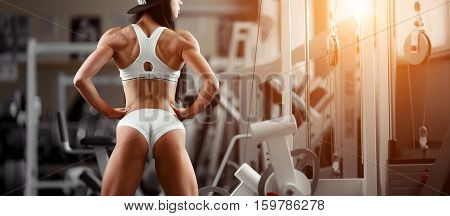 Crossfit woman standing with her back in the gym. Fitness woman, trained body, fitness model. Bodybuilder woman in the gym. Perfect fitness woman sexy buttocks in lingerie. Fitness and bodybuilding