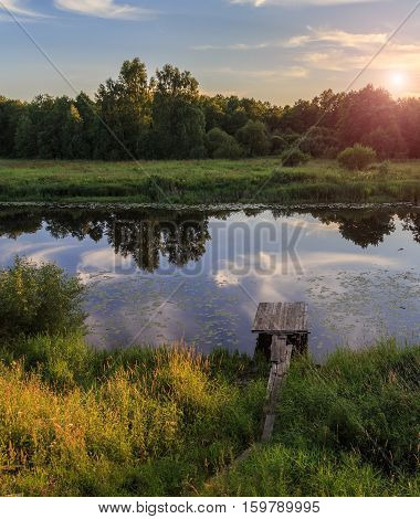Summer Evening on the river, water lilies, small wooden footbridge leads to the water