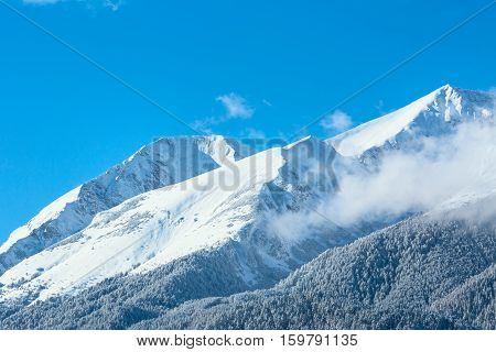 Winter travel vacation nature panoramic background with snow covered mountain peaks and blue sky with clouds closeup, Pirin, Bulgaria