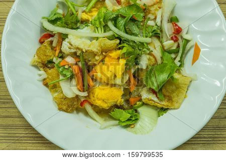 spicy salad with fried eggs on white plate