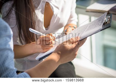 Businesswoman signing contract or agreement between comapnies from different contries while working in office interior. Business or freelance concept.