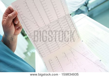 Doctor analyzing ECG chart in patient ward.