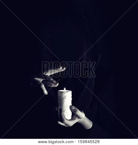 Warlock Holds Hands Over Burning Candle In Darkness