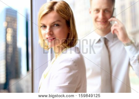 Portraits of business woman and man standing near window
