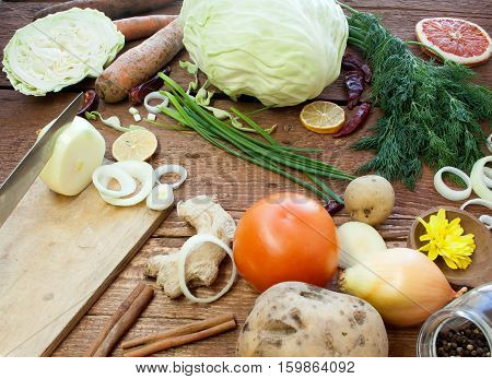Organic vegetables on a wooden surface. Onions potatoes carrots green onions dill ginger tomato pepper. Rustic style. A realistic view of vegetables.