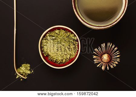 Chasen - special bamboo whisk, spoon for matcha tea and beverage with apetite foam. Black background. Photo made in flat lay style. Focus is on matcha foam.