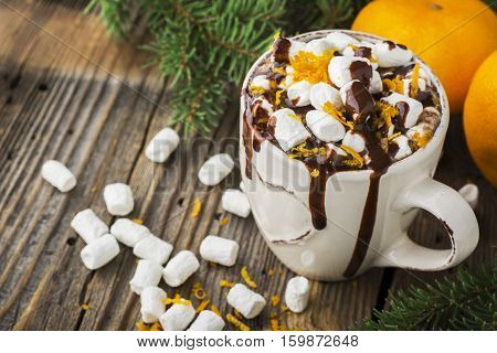 A cup of hot cocoa with chocolate orange and orange zest on a dark wooden background. selective focus