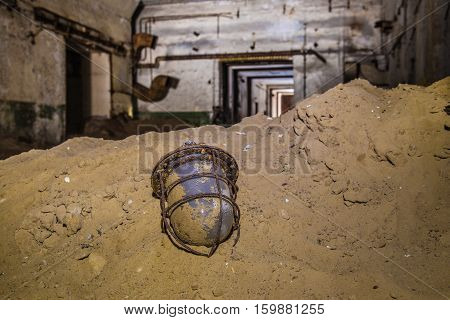 Old broken rusty soviet lantern in the sand on background of abandoned soviet bunker