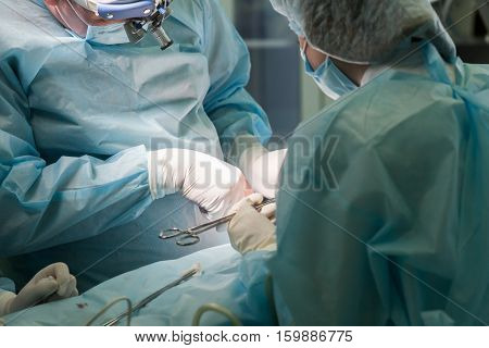 Surgeon and his assistant performing nose reshaping in hospital operating room. Surgical team during medical procedure. Nose job augmentation. Rhinoplasty