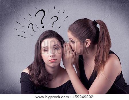 A teenager girl looking confused with drawn question marks above the head, while a girlfriend whispers something in her ear concept.