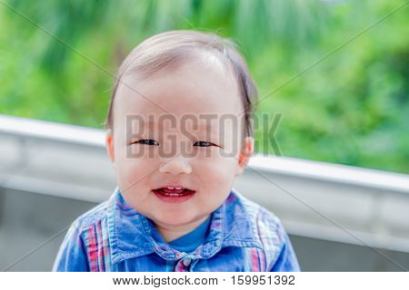 cute baby look somewhere and smile happily in the park asian