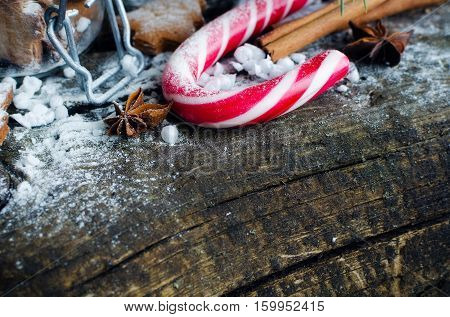 Christmas homemade gingerbreadcookies, cinnamon, anise and red candy cane on old wooden table with fir tree. Christmas treats concept. Christmas background. Selective focus. Copy space.