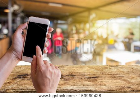 Women hand holding mobile smart phone with coffee shop blur background with copy space. Customer at restaurant blur background with bokeh vintage colorfood online call shopping