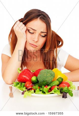 triste mulher sentada perto de chapa, com legumes e cansado da dieta