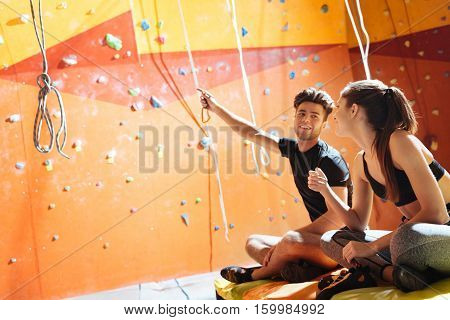 Feel good. Happy young active couple giving high five while sittiing in a climbing gym after training.