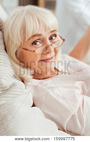 Have a nice day.Portrit of delighted smiling woamn lying in bed bad and looking at you while resting at home