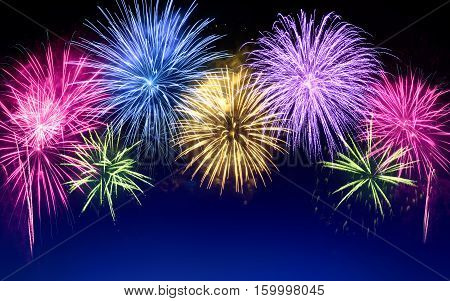 Gorgeous multi-colored fireworks as an arch shaped border on dark blue background ideal for New Year or other celebration events