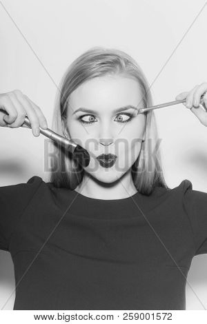 Woman Squinting Eyes On Duck Face With Red Lips. Funny Girl With Makeup Brushes And Long Blond Hair 