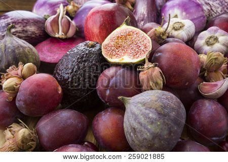 Background Of Fresh Vegetables And Fruits. Purple Eggplant, Plums, Figs, Apples, Avocado, Hazelnuts 