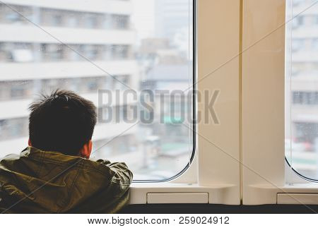 Back Side Of Little Boy Traveling By Train And Looking Out Through Glass Window, Child Problem Or Tr