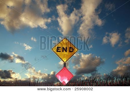ein Ende-Zeichen liegt am Ende einer Straße gegen einen blauen Himmel mit erstaunlichen fluffy clouds