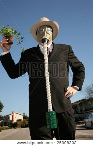 素敵なスーツと、ガスマスクで環境に優しいビジネス男 t を保存する緑の植物を保持します。