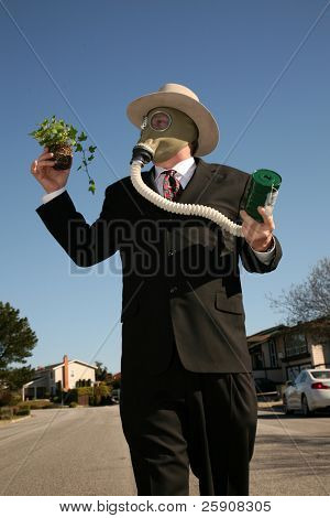 素敵なスーツと、ガスマスクで環境に優しいビジネス男 t を保存する緑の植物を保持します。