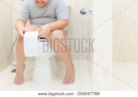 Child Sitting In Toilet And Holding Tissue Roll