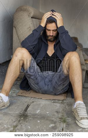 Depressed, Desperate Young Man Sitting On The Building Rooftop Terrace, Wearing Hoodie, Holding Head