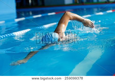Image of athlete man in blue cap swimming in pool