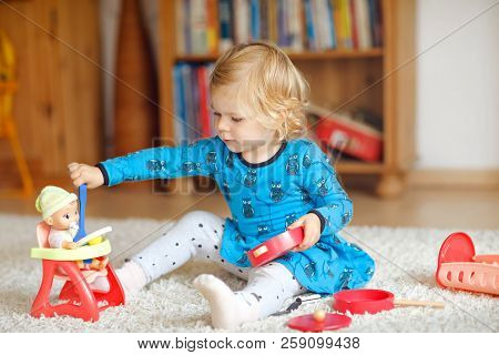 Adorable Cute Little Toddler Girl Playing With Doll. Happy Healthy Baby Child Having Fun With Role G