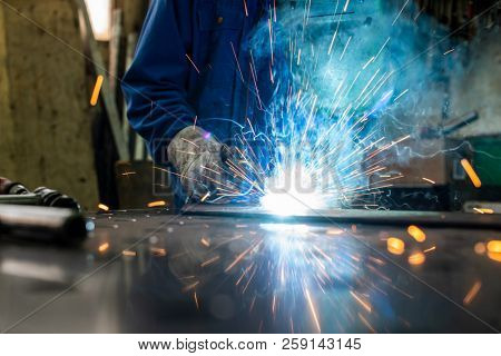 Welder in his workshop welding metal, lots of sparks flying around