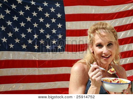 una donna si gode una ciotola di cereali con latte e lamponi una mattina davanti alla sua bandiera americana