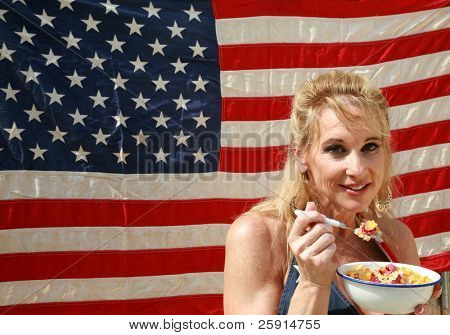 una donna si gode una ciotola di cereali con latte e lamponi una mattina davanti alla sua bandiera americana