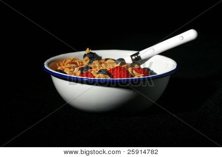 colpo basso studio chiave di una ciotola di cereali con fragole e mirtilli isolati su sfondo nero