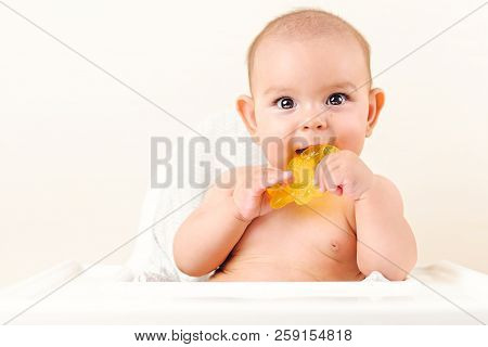 Cute Baby Infant Kid Biting Sitting In Highchair And Chewing Yellow Eething Toy Copy Space Bright Mi