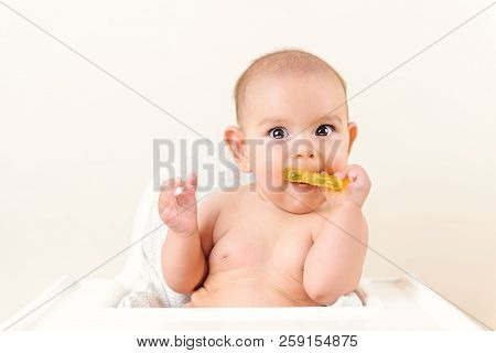 Cute Baby Infant Kid Biting Sitting In Highchair And Chewing Yellow Eething Toy Copy Space Bright Mi
