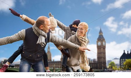 family, travel and tourism concept - happy mother, father, daughter and son having fun over big ben tower in london city background