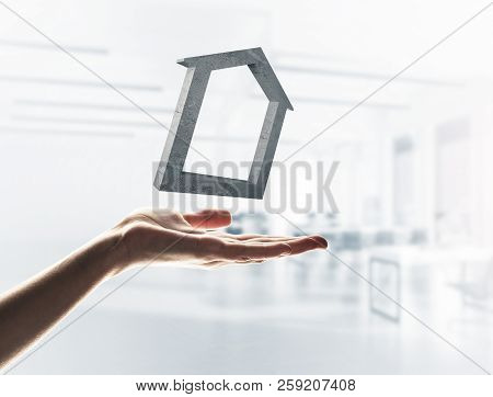 Close Up Of Hand Presenting Stone House Symbol In Palm. Mixed Media