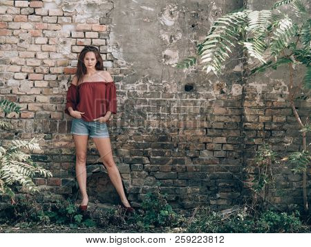 Beautiful woman standing outdoor at rustick brick wall