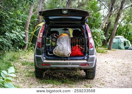 Back View Of Opened Car Trunk Packed Full Of Luggage Bags In Nature Camp