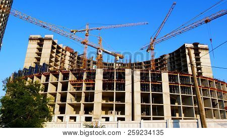 Four Tower Cranes Erect An Office Building. A Commercial Building Under Construction. Construction S