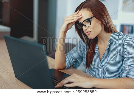 Young Disappointed Feelancer Woman Reading Bad News On Laptop Indoors