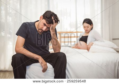 Worried Stress Man Sitting On Bed With Hand On Forehead In Bedroom In Serious Mood Emotion With Preg
