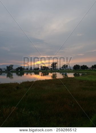 Landscape With A Lagoon With Trees On The Shore, During The Sunset